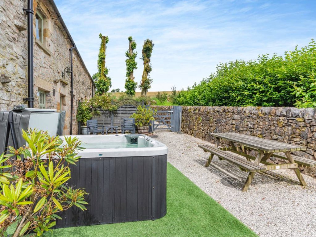 Private hot tub and picnic table in a stone cottage courtyard