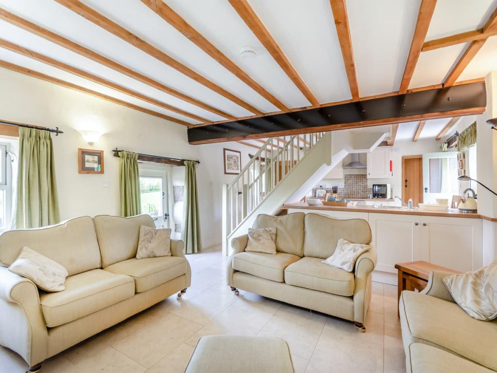 Open-plan cottage living room and kitchen with exposed beams
