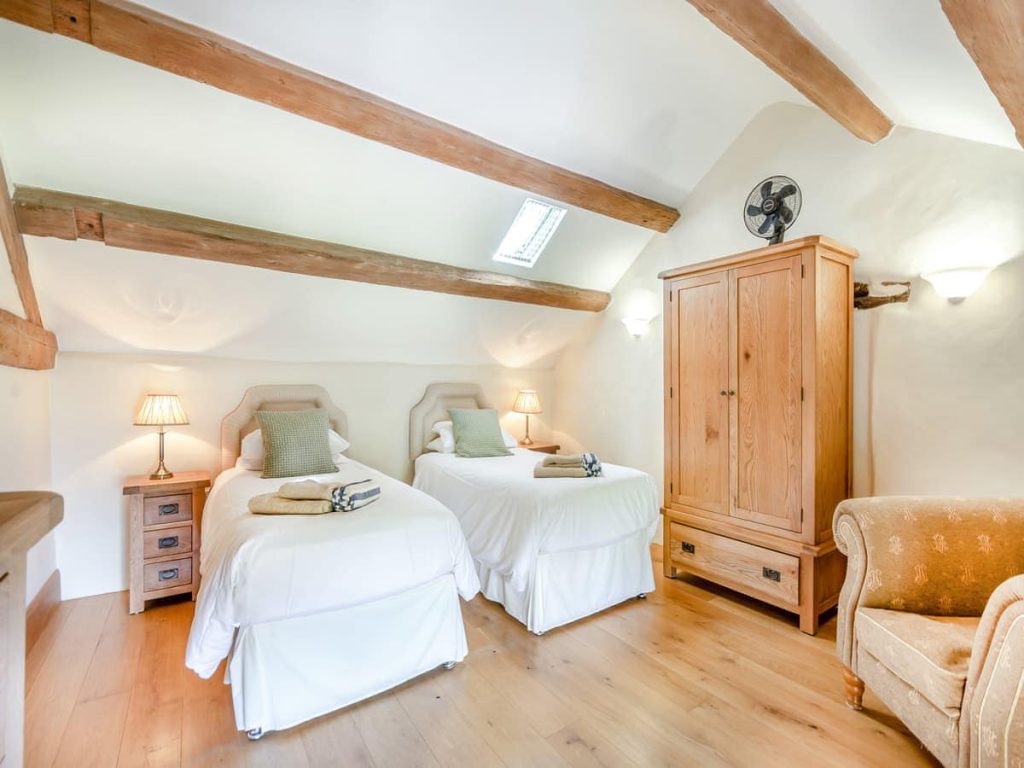 Twin cottage bedroom with exposed beams and wooden wardrobe