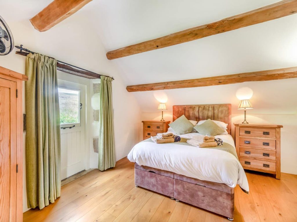 King-size cottage bedroom with exposed wooden ceiling beams